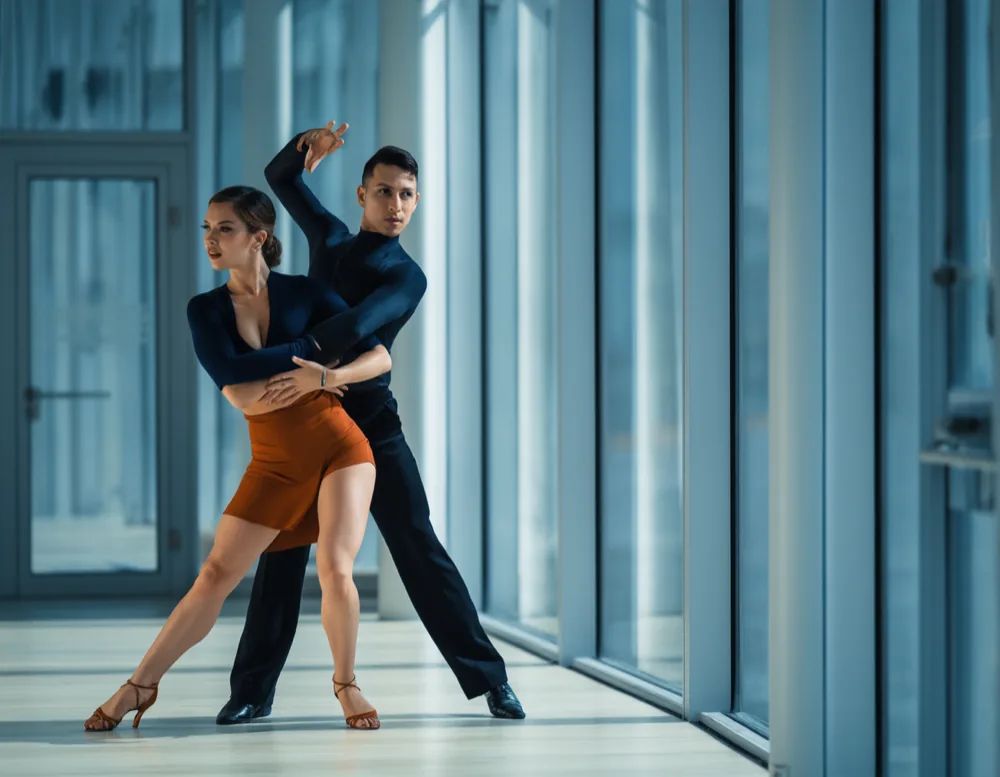 Two dancers practising a partner turn beside the glass wall over the harbour