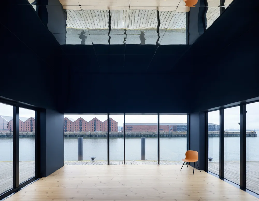 Empty glass-walled dance studio with birch floor looking onto harbour water