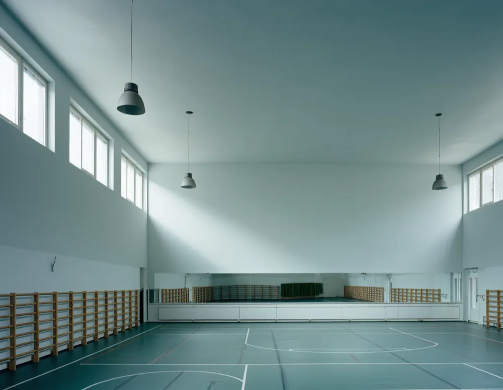 Empty converted gymnasium with wall bars, a mirrored wall and high clerestory windows
